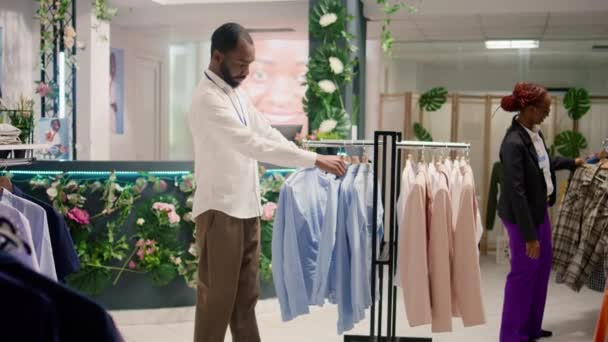 Улыбающийся Помощник Розничной Торговли Раскладывает Одежду Магазине Одежды Торговом Центре — стоковое видео