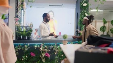 Mağaza müdürü elbise mağazasında müşteriyle konuşuyor. Döndükten sonra aldığı kıyafetleri iade etme işlemini anlatıyor. Müşteri kişisel bilgi verirken satıcı not alıyor