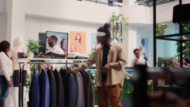 Müşteri tanıtım sezonunda giyim mağazasına gelip gardırobunu doldurmak için ucuz kıyafetler almak istiyor. Moda butiği satışlarından yararlanan adam zarif ceketlere bakıyor.