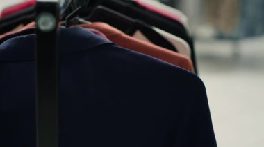 Raflarda şık kıyafetler olan boş prim moda butiği, yakın çekim. Alışveriş merkezindeki modaya uygun giyim mağazasında spor ceketleri ve diğer giysi askıları.