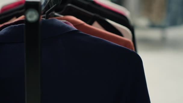 精品店精品精品精品 衣橱典雅 近景拍摄 购物中心的时尚服装店里 大街上的男人在衣架上穿西装和其他衣服 — 图库视频影像