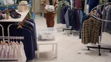 Moda butiğindeki Afrikalı Amerikalı müşteriler iyi bir amaç için kıyafetlerini bağışlıyorlar. Müşteriler bağış kutusuna giysi koyar, giyim mağazasında hayırseverlik jestleri yapar.