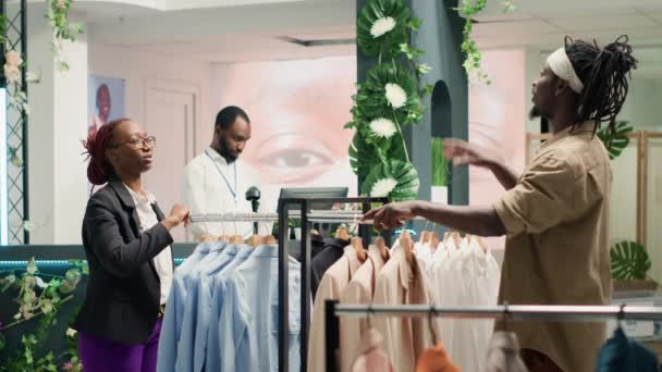 拡張現実技術を使用して衣料品店の小売業者は 彼が選ぶクライアントの衣服のオプションを示しています Arホログラムを使用する従業員は 顧客が必要な服装を可視化するのに役立ちます — ストック動画