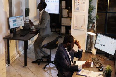 Sinirli çılgın işadamı şirket stratejisinde çalışırken sorun yaşıyor, pazarlama grafiği raporuna bakıyor. Girişimci yönetici şirket kârını artırmak için iş fikirleri üretiyor.