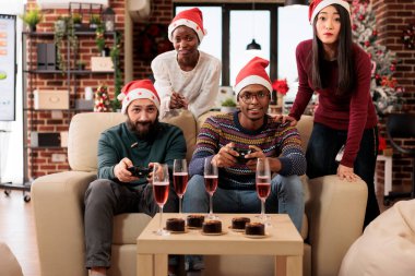Mutlu çalışma grupları Noel 'i birlikte kutlarken festival dekoratif ofisinde video oyunu oynuyorlar. Oyun kağıtlı meslektaşlar iş yerindeki yeni yıl kurumsal partisinde eğleniyorlar.