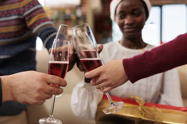 Diverse colleagues toasting and clinking glasses filled with sparkling wine, celebrating christmas together. Employees drinking alcohol and saying cheers on new year holiday in office