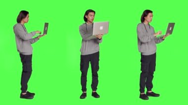 Modern adam dizüstü bilgisayarda internet sayfasında geziniyor, tüm yeşil ekran arkaplanı üzerinde duruyor, kablosuz bilgisayar kullanarak online web sitesine göz atıyor. Sosyal medya sayfasını kontrol eden genç adam iş üzerinde çalışıyor.