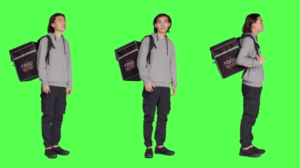 年轻人用热背包运送食物 站在工作室的全身绿屏前 亚洲人送货员携带外卖食品袋 向客户下订单 — 图库视频影像