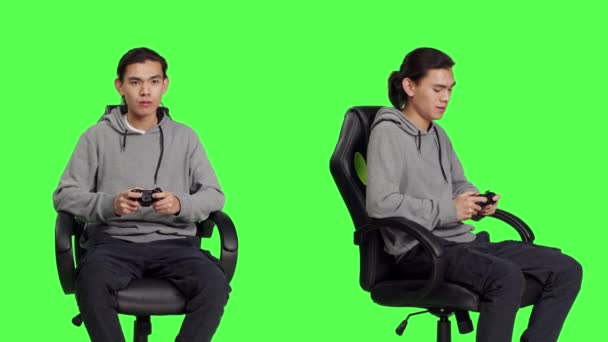Азіатський Хлопець Використовує Контролер Геймплею Сидячи Стільці Проти Зеленого Тла — стокове відео