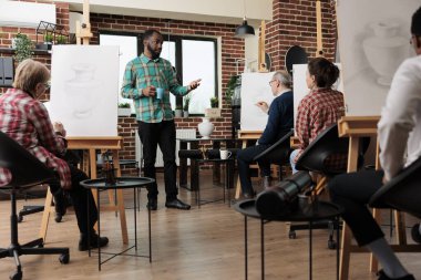 Bir grup insan resim stüdyosunda resim çizmeyi öğreniyor, grup derslerinden zevk alıyor, sınıfta birlikte çalışıyorlar. Yetişkinler için sanatsal beceriler geliştirmek ve stresi azaltmak için yaratıcı faaliyetler