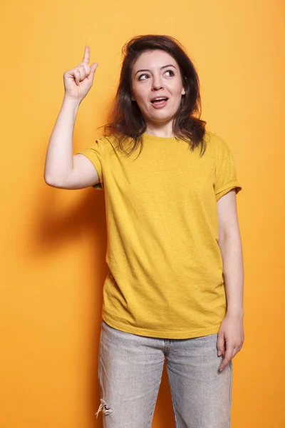 一个积极的女人站在孤立的橙色背景上 食指指向上方 在演播室里 白种人的成年女性在做手势和向上看的时候 有了一个很好的想法 — 图库照片