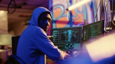 Afro-amerikan başlıklı hacker yeraltı üssünde saklanıyor, endişeyle etrafa bakıyor, virüs kullanarak kurbanlardan veri çaldıktan sonra gergin hissediyor, kolluk kuvvetlerinden kaçmaya çalışıyor.