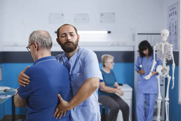 整形外科医は脊椎と肩を伸ばし 理学療法のために怪我をした 身体回復のための背中の痛みを持つ退職した老人に助けを与える医師 ストック写真
