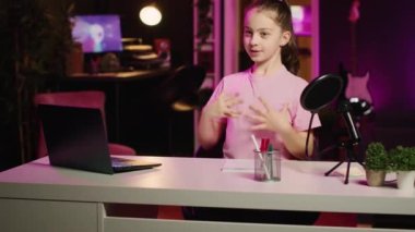 Neşeli zombi çocuk pembe ışıklı oturma odasında online platformlar için video çekiyor, gününden bahsediyor. İzleyicileri eğlendiren, içerik oluşturma işini profesyonel kayıt cihazlarıyla yapan çocuklar