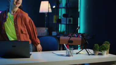 Çocuk kişisel stüdyoya RGB ışıklarıyla aydınlanmış bir şekilde geliyor ve internet video çekimine başlıyor. İç dekorla dolu loş ışıklı oturma odasında film çeken genç bir kız.