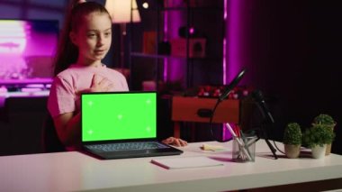 Stüdyodaki çocuk etkileyicisi kayıt cihazlarını kullanarak model dizüstü bilgisayarın incelemesini kaydediyor. Genç kız çevrimiçi şov sunucusu, izleyiciler için izole edilmiş ekran defteri sunuyor.