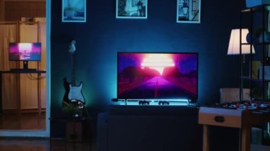 Boş ev stüdyosunun çekimleri internet video yapımında kullanılan neon ışıklarla aydınlatıldı. İçerik oluşturma ekipmanlarıyla dolu oturma odası, arka planda çalışan TV animasyonları