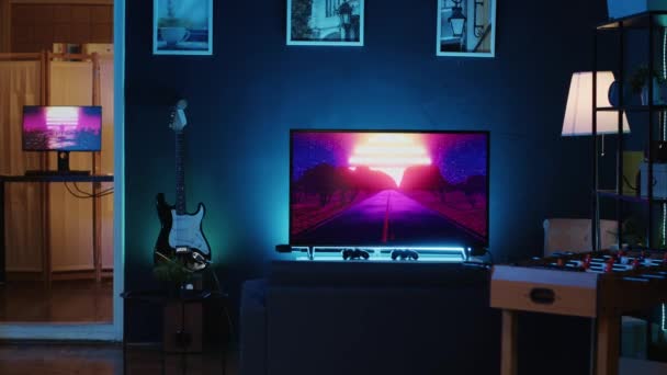 インターネットビデオ制作に使用されるネオンライトで照らされた空のホームスタジオのパンニングショット コンテンツ制作装置 バックグラウンドで実行するテレビアニメでいっぱいのリビングルーム — ストック動画