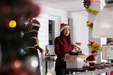 Asyalı yönetici ofis dekorasyonu yapmak ve çalışanları neşeli Noel havasına sokmak için bayram süslerini açıyor. Şirket yönetimi yöneticisi xmas için çalışma alanını dekore etmeye hazırlanıyor