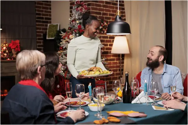 Festive family at christmas eve dinner, celebrating winter season event together in december. Diverse people eating seasonal food and drinking wine, feeling joyful during traditional celebration.