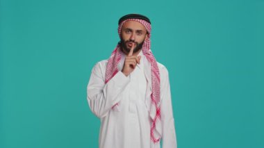 Arap adam sessiz sedasız işaret veriyor. Stüdyoda sessiz jestler yapıyor. Gizli gizlilik sembolünü kameraya sunan özel bir model, sır ve mahremiyet saklamaya çalışıyor.