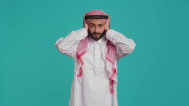 Yetişkinler kamerada geleneksel Müslüman kıyafetleri ve eşarplarıyla üç bilge maymun işareti yapar. Metafor, kavram ve metafor göstermek için gözlerini, ağzını ve kulaklarını kapatan genç bir adam..