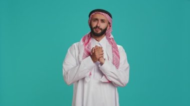 Umut dolu Arap bir adam bir şey için yalvarıyor ve yalvarıyor, bir duada el ele tutuşuyor ve inancını gösteriyor. Ortadoğulu çaresizce yardım arıyor, mavi stüdyoda umudu var..