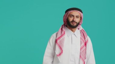 Müslüman kişi, Arap kültürünü geleneksel cübbe ve başörtüsüyle gösteren bir şey hakkında hoşnutsuzluk ve hoşnutsuzluk duyuyor. Reddetme ve olumsuz jest gösteren genç..