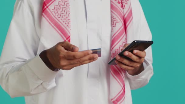 銀行サービスを利用してスマートフォンインターネットストアで商品を支払うイスラム教徒 携帯電話でクレジットカード番号をコピーするアラブ人 割引シーズン中にオンラインショッピング — ストック動画