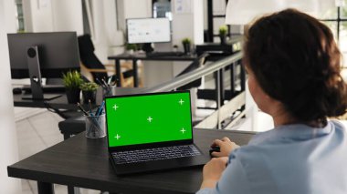 Çalışan dizüstü bilgisayarda yeşil ekran düzeni kullanır, iş operasyonları ve pazarlama görevleri üzerinde çalışır. Uzman, açık ofiste izole edilmiş bir kopya uzay şablonu ile bilgisayarı inceliyor. El kamerasıyla..