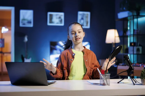 Young content creator using professional recording camera and microphone to do livestream. Kid online streamer using video production gear to do live broadcast for her audience