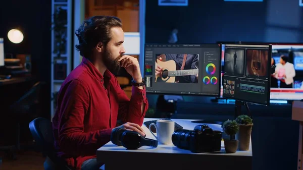 Videographer using editing software to assemble footage into cohesive final result, color correcting it to ensure project meets desired aesthetic, working in creative studio