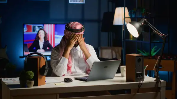 ムスリム起業家は 自宅で働いている片頭痛に苦しんでいます 個人のアパートのオフィスでノートパソコン中東の人を使用しながら 過労から頭痛を得る電子メールに答える — ストック写真