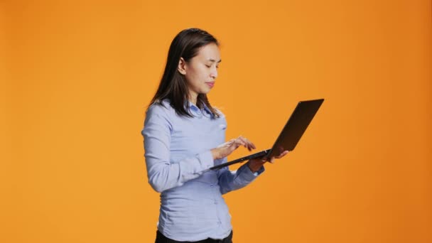 在工作室的笔记本电脑上随意上网浏览的人 在带有橙色背景的无线个人电脑上寻找灵感 亚洲妇女在互联网上浏览网页 搜索项目 — 图库视频影像