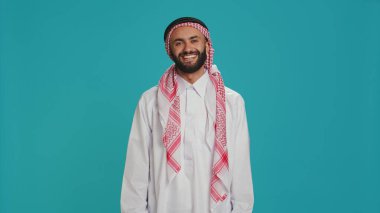 Stüdyoda başını sallayarak evet diyen ve onayını veren müslüman bir adam. Geleneksel kıyafetli bir Arap bir şeye destek veriyor. Orta Doğulu adam olumlu ve anlaşma imzası atıyor..