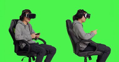 Genç adam yeşil ekran arka planına karşı birden fazla aygıt kullanarak diğer insanlarla oyun oynarken web tabanlı çatışmalara giriyor. Sanal gerçeklik gözlükleriyle, adam neşeli görünüyor..