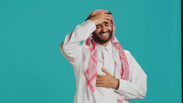スタジオでジョークを笑いながら イスラム教徒の伝統衣装やカティヤを着て楽しんでいる陽気な人 人々と笑って楽しむ若いアラブ人 幸せと喜びを表現する — ストック写真