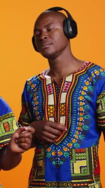 Dikey Video Etnik çift kamerada hayali gitar çalıyormuş gibi yapıyor, kulaklıkla müzik dinleyip stüdyoda müzik aleti çalarken eğleniyorlar. Afrikalı Amerikalı erkek ve kadın