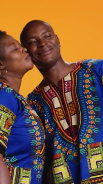 Dikey Video Mutlu Afrikalı Amerikalı çift stüdyoda hoş bir anı yakalıyorlar, akıllı telefondan fotoğraf çekiyorlar ve boş zamanların tadını çıkarıyorlar. Romantik evli insanlar telefonda hatıralar için fotoğraf çekerler..