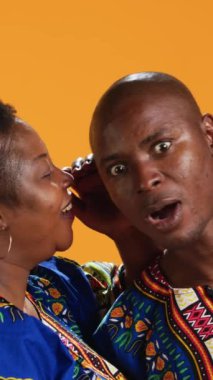 Dikey Gülümseyen Kadın kocasıyla önemli bir sırrı paylaşıyor, kulağına fısıldıyor ve dedikodu yapıyor. Şok olmuş bir adam eğilip gizli bilgileri, gizlilik kavramını dinliyor..