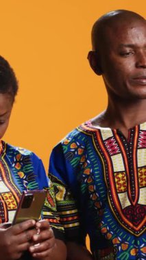 Dikey Video Geleneksel Etnik İnsanlar online video konferansında sohbet ediyor, akıllı telefon webcam 'ine el sallıyor ve aile ya da arkadaşlarla konuşuyor. Gülümseyen adam ve kadın video çağrısında sevdikleriyle buluşuyor..