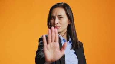 Filipinli kadın avuç içi ile dur işareti gösteriyor, negatiflik reklamı yapıyor ve kamerada sembol yok. Stüdyoda resmi kıyafet giyen bir kadın model reddediliyor ve bir şeyi reddediyor..