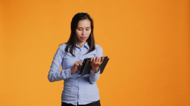 Asyalı model internetten tablet kullanarak kıyafet alıyor, online alışveriş çılgınlığı için internet sitesine kredi kartı bilgileri yazıyor. Gayri resmi giyinmiş güzel bir kadın bir şeyler satın alıyor..
