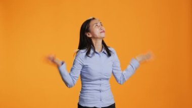 Turuncu arka planda İsa 'ya dua eden ruhani bir kadın dua sırasında Tanrı' ya şükranlarını sunar. Dine inancını ve inancını gösteren Asyalı barış istiyor..