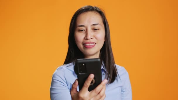亚洲女人在录音室里回答在线视频 在网上与人进行远程连接 年轻的成年人微笑着在手机屏幕上挥手 背景上的在线视频会议 — 图库视频影像