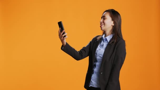 菲律宾员工在网上通过智能手机连接 站在橙色背景之上 有信心的年轻妇女在因特网上回答视频会议连接问题 — 图库视频影像