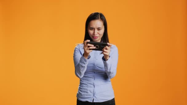 快乐的成年人在相机上玩手机游戏 在智能手机网络上玩现代射击比赛的乐趣 使用电话娱乐和休闲的亚洲妇女 — 图库视频影像