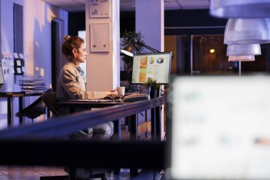 Finans stratejisinde gece geç saatlere kadar çalışan girişimci şirket kârını artırmak için iş fikirleri üretiyor. Girişim ofisinde masa başında oturan iş kadını, pazarlama grafiklerini analiz ediyor