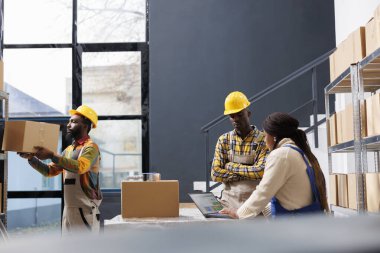 Afro-Amerikan depo yöneticileri dizüstü bilgisayardan bilet seçmeyi tartışıyor. Tüm siyah ecommerce mağaza çalışanları depolama odasında çalışıyor ve dağıtım için alıcı siparişi hazırlıyor