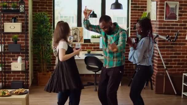 多民族学校の同僚がアパートパーティーを企画し エレクトロニック ミュージックに熱心に踊っている 一緒に過ごした時間を楽しむ笑顔の友達 ダイナミックなダンスの動きに打ち込む — ストック動画